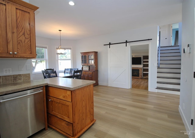 kitchen with dishwasher, a barn door, brown cabinetry, and a peninsula