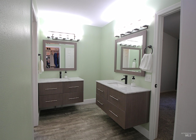 full bath featuring two vanities, wood finished floors, and a sink