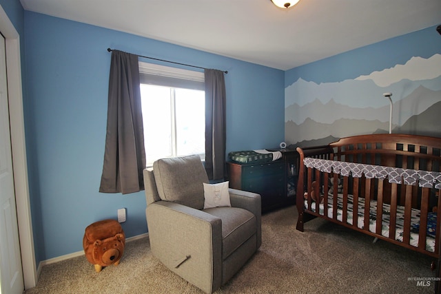 carpeted bedroom featuring a nursery area and baseboards