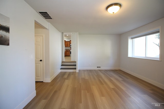 unfurnished room featuring visible vents, baseboards, and light wood-style floors