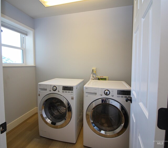 laundry area featuring light wood-type flooring, baseboards, separate washer and dryer, and laundry area