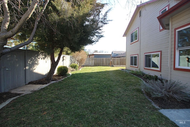 view of yard featuring an outbuilding, a storage shed, and a fenced backyard