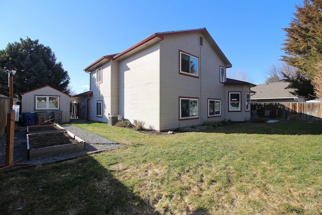 rear view of property with fence, cooling unit, a yard, an outdoor structure, and a vegetable garden