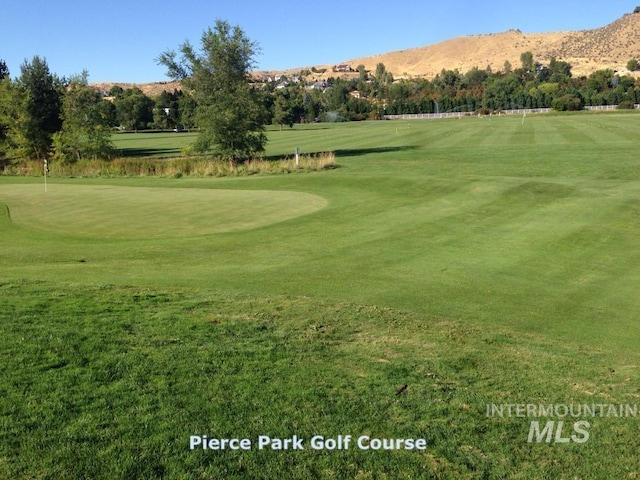 surrounding community with golf course view, a lawn, and a mountain view