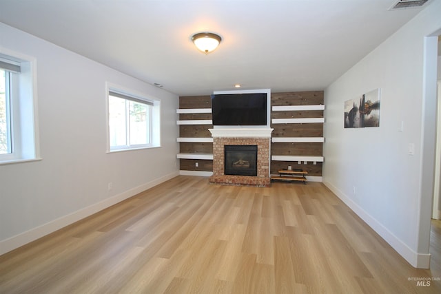 unfurnished living room featuring visible vents, baseboards, light wood-style flooring, and a fireplace