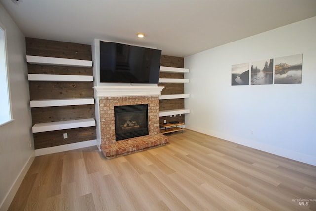 unfurnished living room featuring baseboards, wood finished floors, and a fireplace