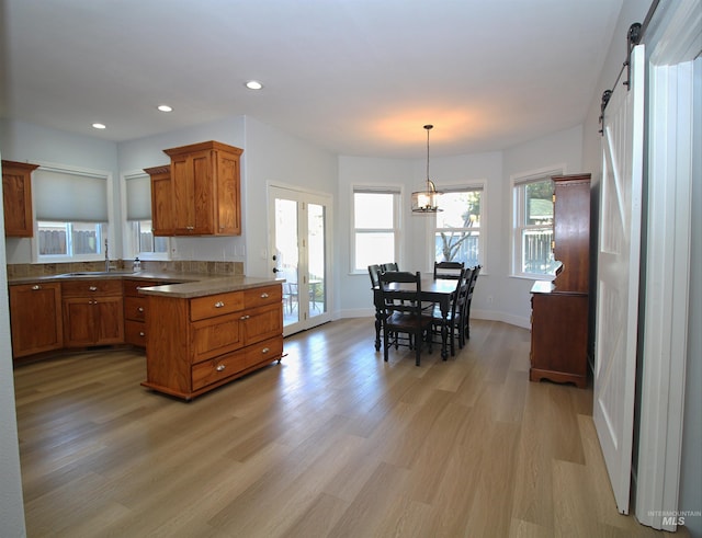 kitchen featuring brown cabinets, light wood-style flooring, a sink, french doors, and a barn door