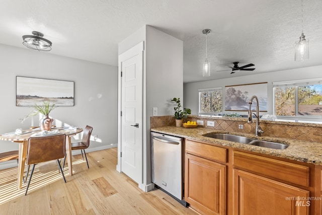 kitchen featuring dishwasher, light wood-style flooring, a sink, and plenty of natural light