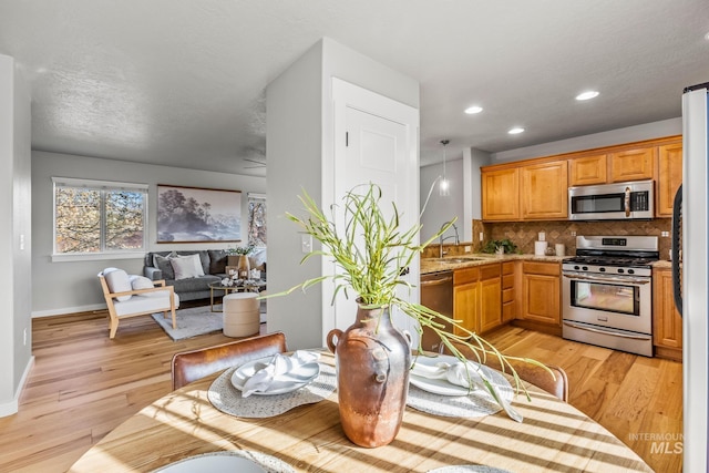 kitchen with decorative backsplash, a sink, stainless steel appliances, and light wood finished floors