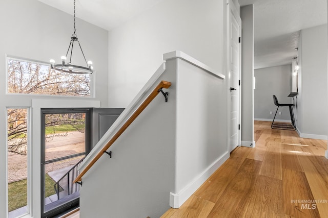 foyer with light wood finished floors, baseboards, a towering ceiling, and an inviting chandelier
