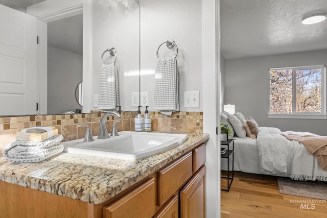 bathroom featuring wood finished floors, decorative backsplash, and vanity