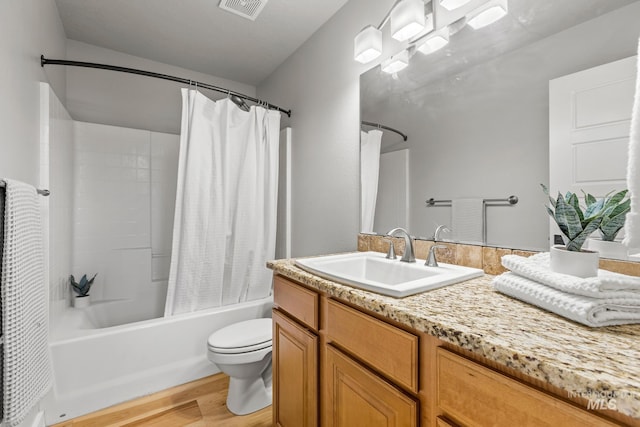 bathroom featuring toilet, vanity, wood finished floors, shower / tub combo, and visible vents