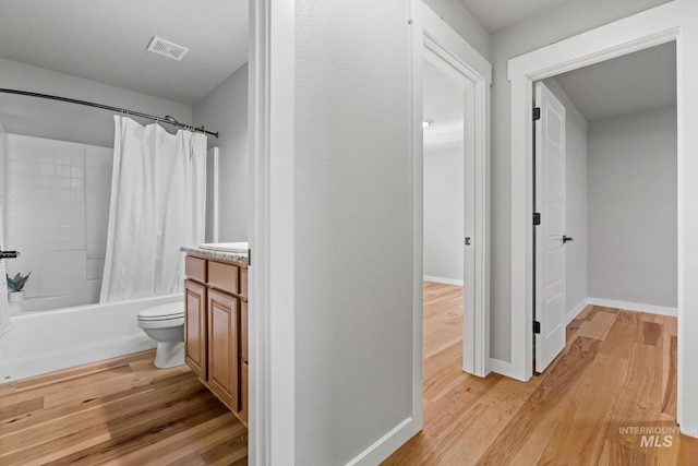 bathroom featuring shower / tub combo with curtain, vanity, wood finished floors, baseboards, and visible vents