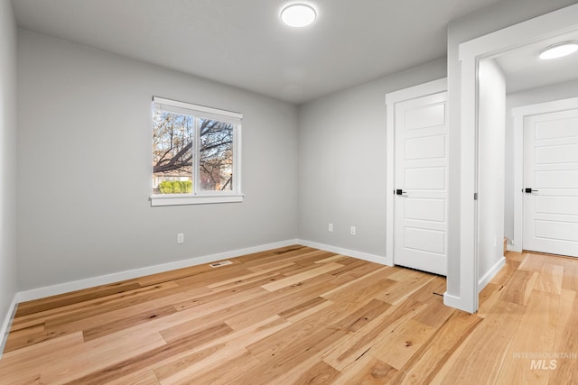 unfurnished bedroom featuring baseboards, visible vents, and light wood finished floors