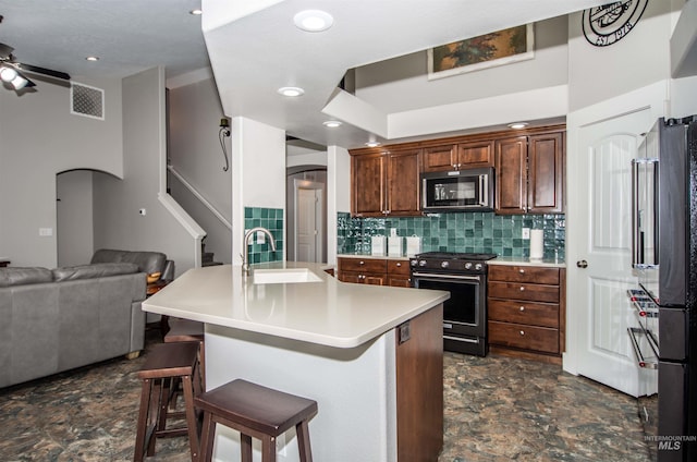 kitchen with stainless steel appliances, ceiling fan, a kitchen bar, decorative backsplash, and sink