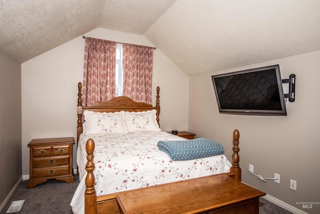 bedroom featuring a textured ceiling, lofted ceiling, and dark carpet