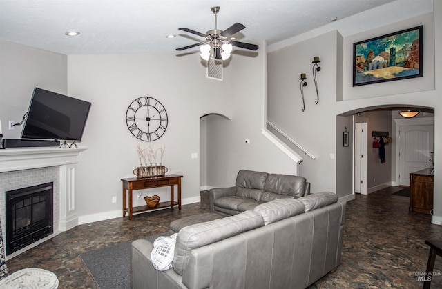 living room featuring a tile fireplace and ceiling fan