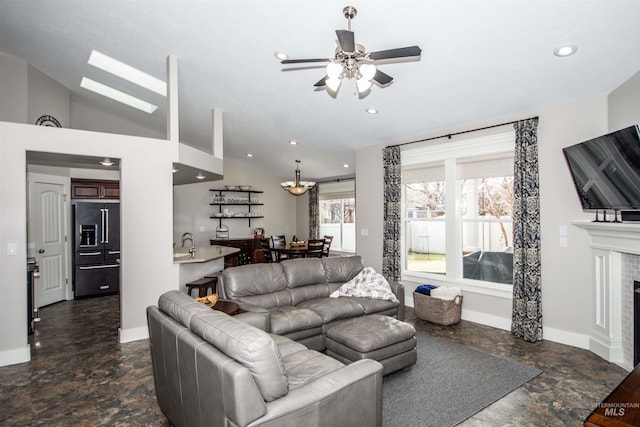 living room featuring ceiling fan, a tiled fireplace, lofted ceiling, and sink