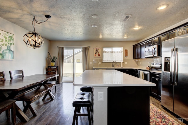 kitchen with visible vents, a sink, wood finished floors, stainless steel appliances, and decorative backsplash