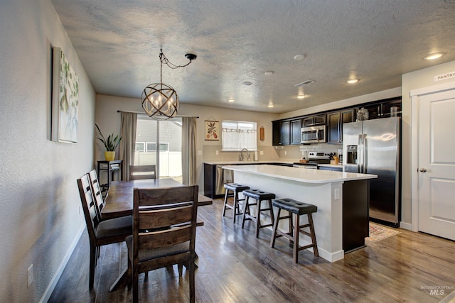 kitchen featuring wood finished floors, a kitchen island, a sink, stainless steel appliances, and light countertops