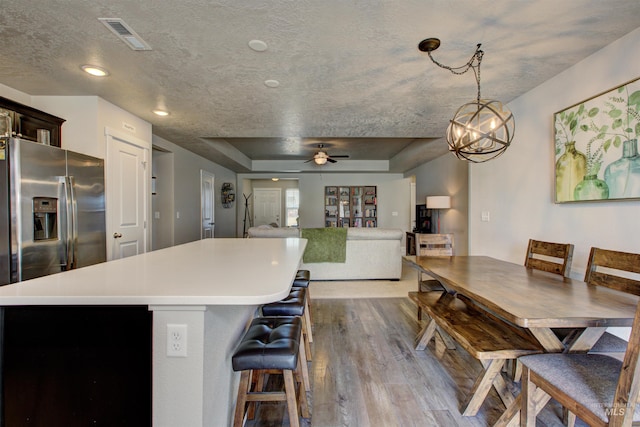 kitchen featuring visible vents, a tray ceiling, dark wood-type flooring, a textured ceiling, and a center island