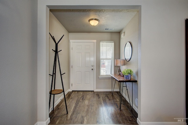 entrance foyer featuring visible vents, baseboards, a textured ceiling, and wood finished floors