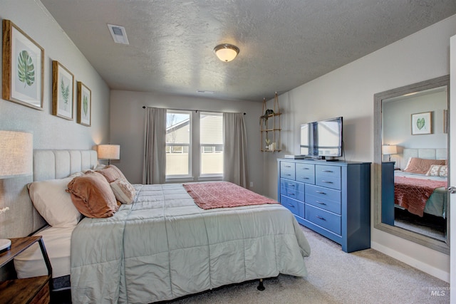 bedroom with visible vents, light colored carpet, and a textured ceiling