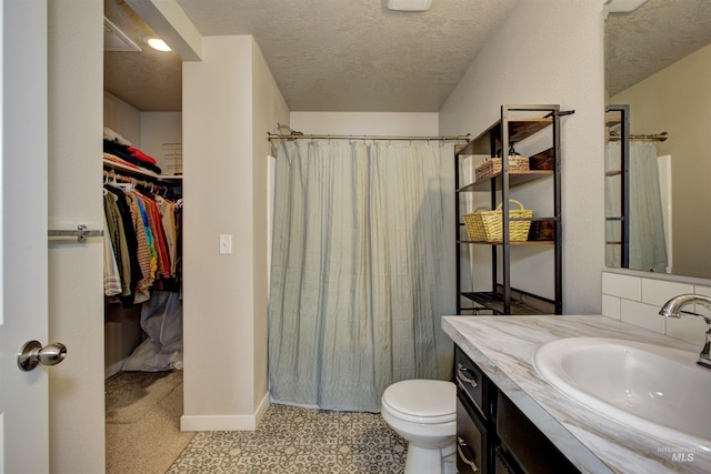 bathroom with vanity, a shower with shower curtain, a spacious closet, a textured ceiling, and toilet