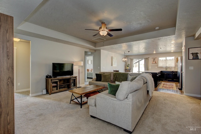 living area featuring a raised ceiling, light colored carpet, baseboards, and visible vents