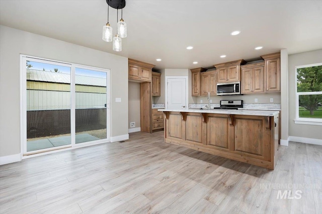kitchen with appliances with stainless steel finishes, decorative light fixtures, light countertops, light wood-style floors, and recessed lighting