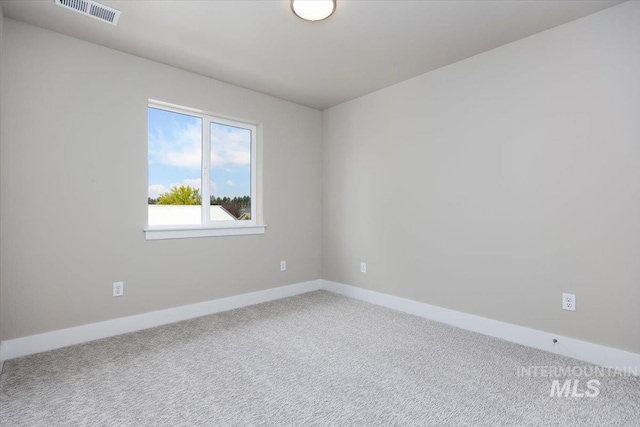 carpeted spare room featuring baseboards and visible vents