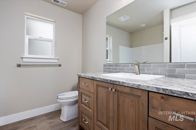 bathroom with tasteful backsplash, visible vents, toilet, wood finished floors, and vanity