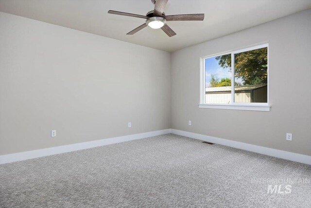 empty room with a ceiling fan, carpet flooring, visible vents, and baseboards