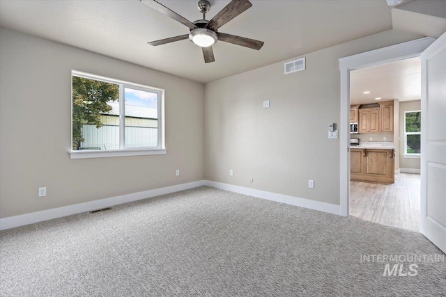 empty room with light carpet, a wealth of natural light, and visible vents