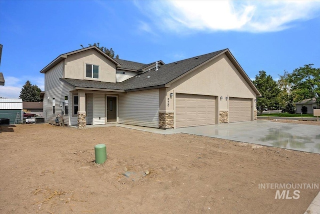 view of front facade featuring stone siding, driveway, an attached garage, and stucco siding