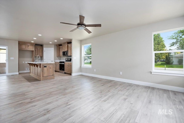 kitchen featuring baseboards, appliances with stainless steel finishes, open floor plan, and light countertops