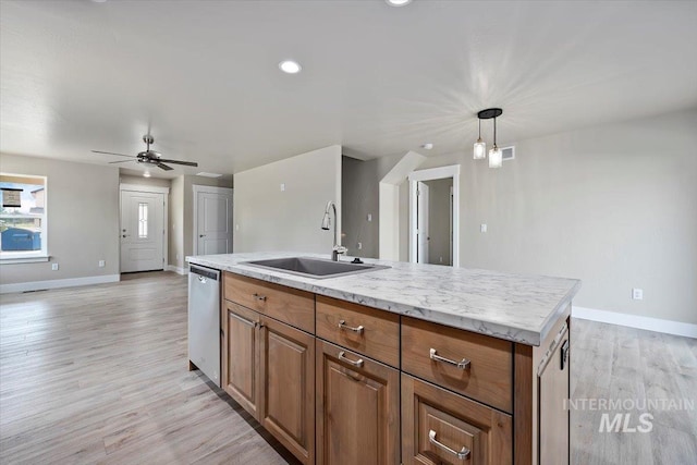 kitchen featuring light wood-style flooring, open floor plan, a sink, dishwasher, and baseboards