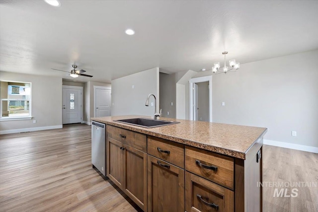 kitchen with light wood finished floors, baseboards, a sink, a kitchen island with sink, and stainless steel dishwasher