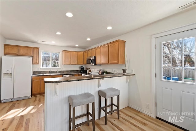 kitchen featuring a peninsula, a breakfast bar area, light wood-type flooring, and stainless steel appliances