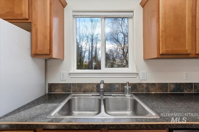 room details featuring a sink, brown cabinets, and dark countertops