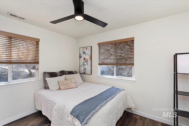 bedroom featuring visible vents, multiple windows, baseboards, and wood finished floors