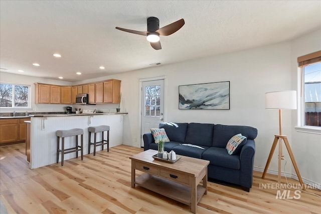 living room with visible vents, baseboards, ceiling fan, light wood-type flooring, and recessed lighting