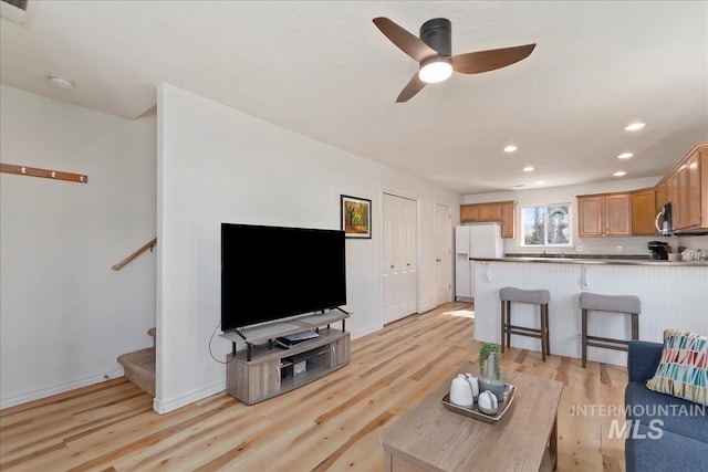 living area with baseboards, light wood-type flooring, stairs, recessed lighting, and a ceiling fan