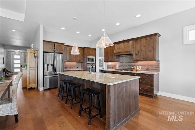 92 S Wildgrass Way, Star, ID 83669 - kitchen with appliances with stainless steel finishes, a sink, a kitchen bar, decorative backsplash, and recessed lighting