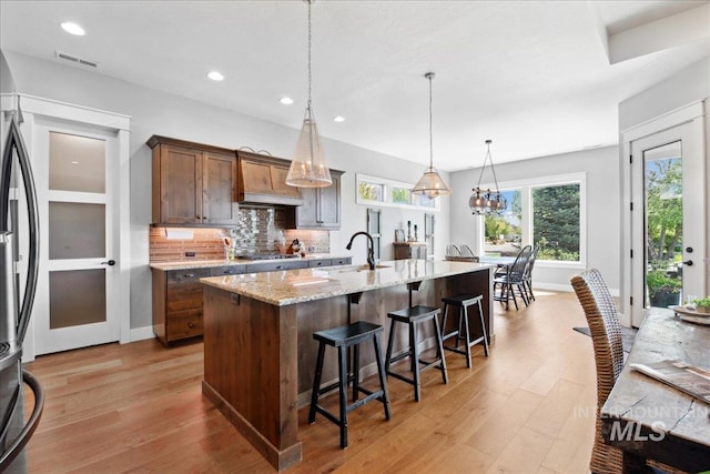 92 S Wildgrass Way, Star, ID 83669 - kitchen with a sink, light wood finished floors, a kitchen bar, decorative backsplash, and recessed lighting