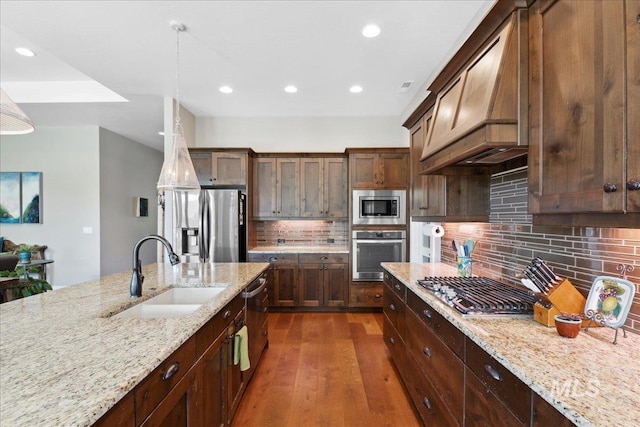 92 S Wildgrass Way, Star, ID 83669 - kitchen featuring appliances with stainless steel finishes, a sink, custom exhaust hood, dark wood-type flooring, and decorative backsplash