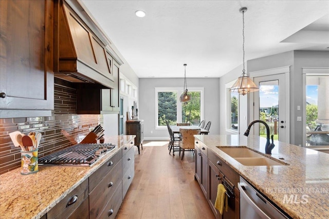 92 S Wildgrass Way, Star, ID 83669 - kitchen with a sink, appliances with stainless steel finishes, decorative backsplash, light wood-type flooring, and decorative light fixtures