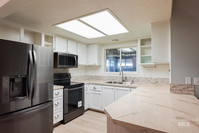 kitchen featuring light hardwood / wood-style flooring, kitchen peninsula, stainless steel appliances, sink, and white cabinets