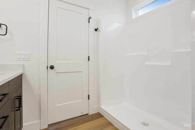 bathroom featuring hardwood / wood-style flooring, vanity, and a shower