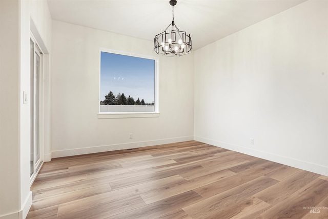 unfurnished dining area with a notable chandelier and light hardwood / wood-style flooring